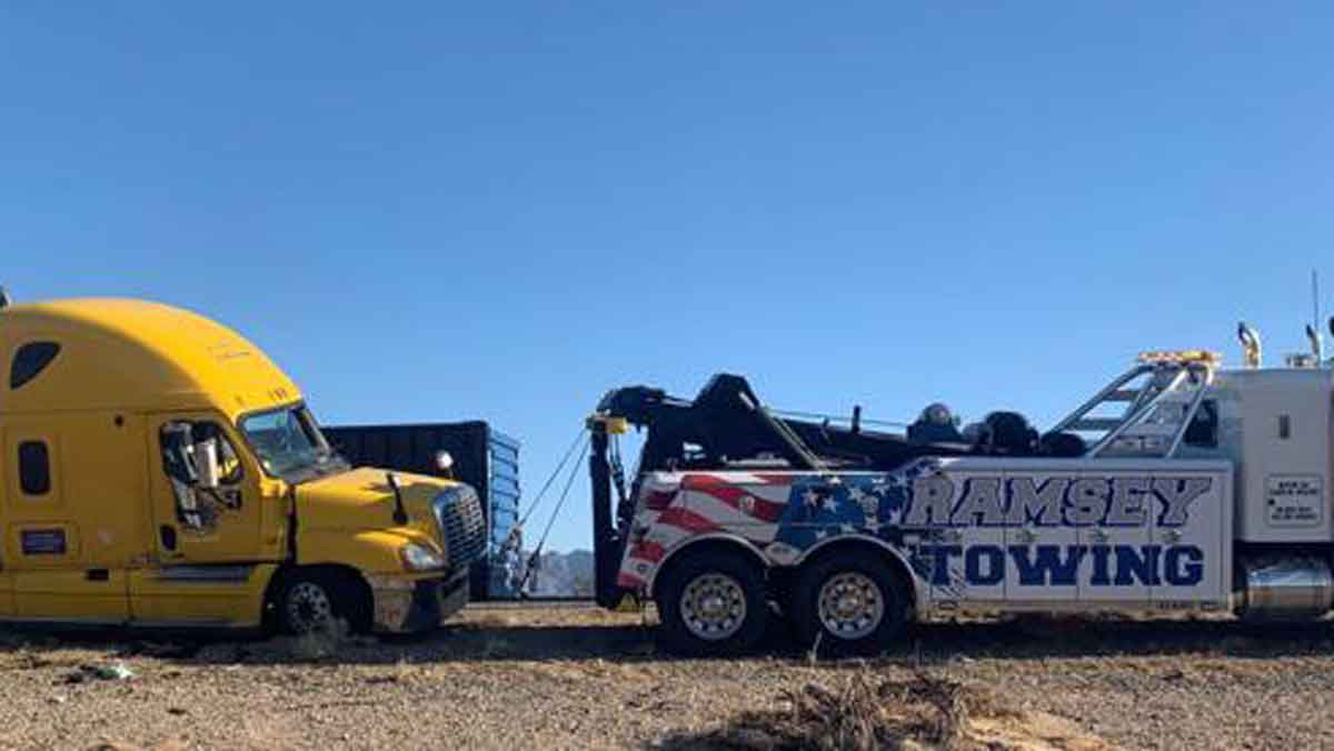 yellow semi-truck being hauled by towing truck