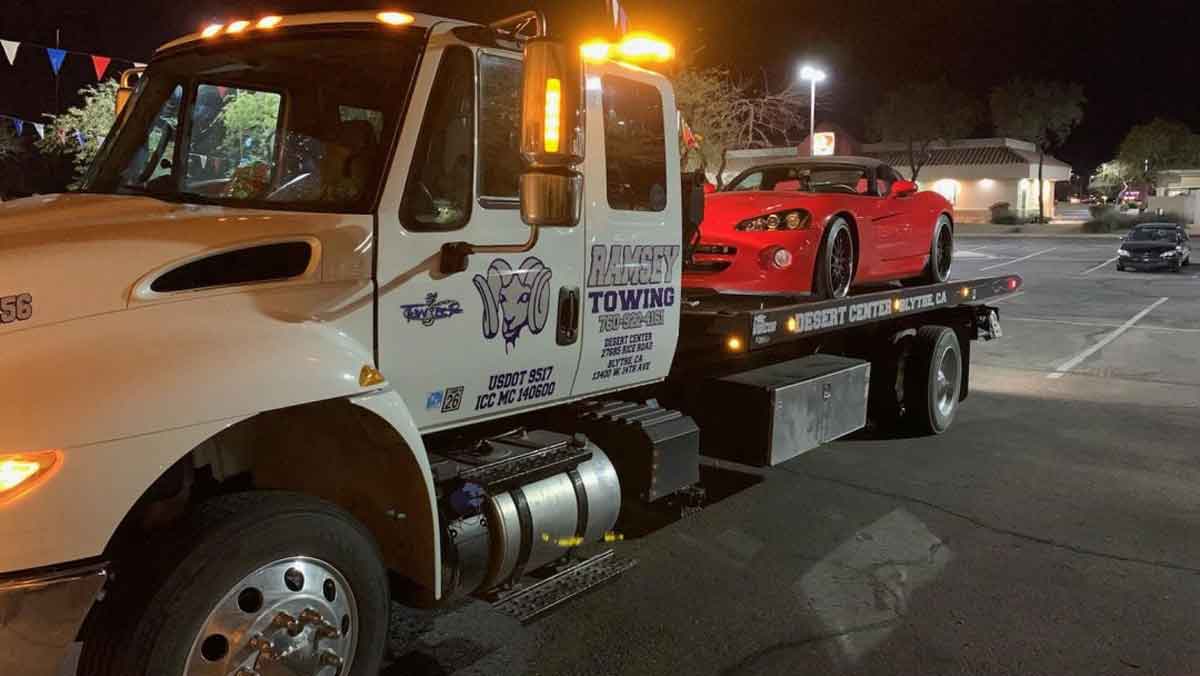Ramsey Towing tow truck hauling red light duty vehicle